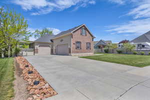 View of front of property with a garage, fence, a front yard, brick siding, and concrete driveway