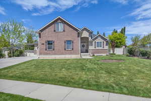 Traditional home with fence, a front lawn, brick siding, an attached carport, and driveway
