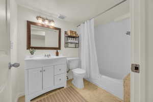 Full bathroom with vanity, shower / bath combo, toilet, and visible vents