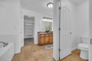 Primary bathroom with vanity, baseboards, a garden tub, and toilet