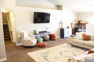 Carpeted living room with vaulted ceiling and a fireplace
