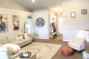 Living room with lofted ceiling and dark carpet