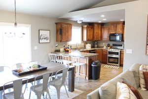 Kitchen featuring light stone counters, light tile floors, sink, range with two ovens, and hanging light fixtures