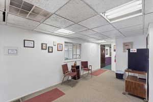 Interior space with carpet floors, visible vents, baseboards, and a paneled ceiling
