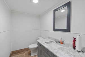 Bathroom with crown molding, wood finished floors, toilet, and vanity