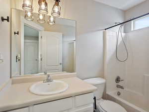 Full bathroom featuring toilet, a notable chandelier, bathtub / shower combination, and vanity