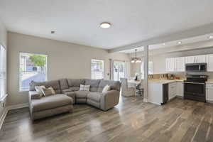 Living area with recessed lighting, an inviting chandelier, a healthy amount of sunlight, and wood finished floors