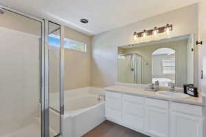 Ensuite bathroom featuring a garden tub, vanity, wood finished floors, ensuite bathroom, and a stall shower