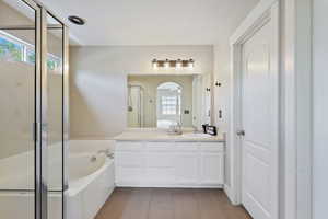 Full bath with a sink, double vanity, a stall shower, and a garden tub