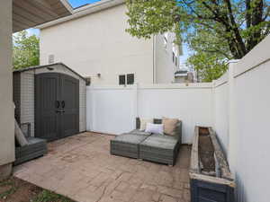View of patio with a fenced backyard, a storage unit, and an outdoor structure