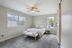 Bedroom with baseboards, a barn door, and carpet