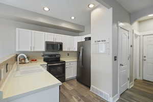 Kitchen featuring visible vents, dark wood-style floors, white cabinets, a sink, and appliances with stainless steel finishes