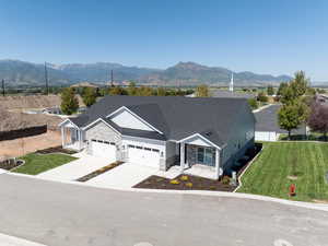 Ranch-style home with concrete driveway, an attached garage, a mountain view, and stone siding