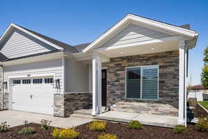 Craftsman inspired home with an attached garage, concrete driveway, and stone siding