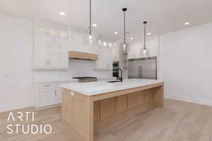 Kitchen featuring built in appliances, backsplash, baseboards, a sink, and white cabinetry