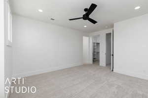 Unfurnished bedroom with light carpet, baseboards, a walk in closet, recessed lighting, and a ceiling fan