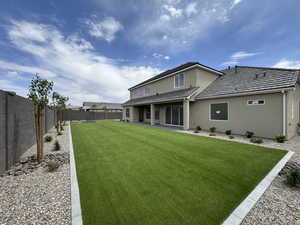 Back of house featuring a lawn, a fenced backyard, stucco siding, and a patio