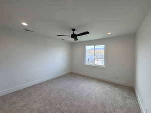 Unfurnished room with a ceiling fan, baseboards, visible vents, and light carpet