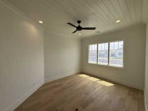 Unfurnished room featuring wood ceiling, a ceiling fan, crown molding, wood finished floors, and baseboards