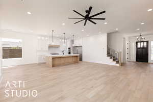Kitchen featuring high quality fridge, open floor plan, light countertops, a sink, and a kitchen island with sink