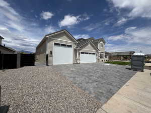 View of front of home featuring fence, stone siding, decorative driveway, board and batten siding, and an attached garage