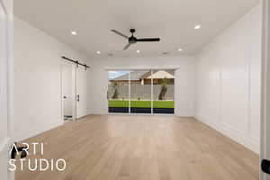 Unfurnished bedroom featuring a barn door, access to exterior, light wood-style floors, baseboards, and recessed lighting