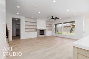 Unfurnished living room featuring ceiling fan, light wood finished floors, recessed lighting, a glass covered fireplace, and baseboards