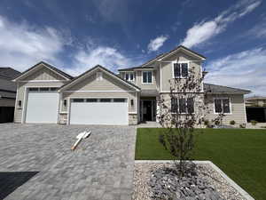 Craftsman-style house featuring a garage, a front yard, stone siding, decorative driveway, and board and batten siding