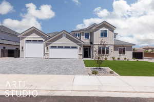 Craftsman-style house featuring a garage, decorative driveway, stone siding, board and batten siding, and a tile roof