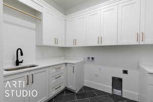 Washroom featuring cabinet space, dark tile patterned flooring, electric dryer hookup, baseboards, and washer hookup