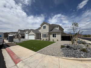 View of front of property featuring an attached garage, stone siding, board and batten siding, a front yard, and driveway