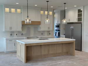Kitchen with light wood-style floors, a kitchen island, stainless steel appliances, and recessed lighting