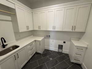 Laundry area featuring hookup for an electric dryer, cabinet space, a sink, baseboards, and hookup for a washing machine