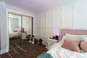 Bedroom featuring carpet floors, a textured ceiling, a decorative wall, and a closet