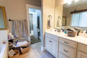Bathroom with vanity, tile patterned floors, and a tub