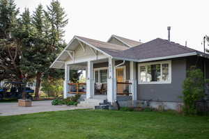 View of front facade with a shingled roof, a porch, and a front lawn