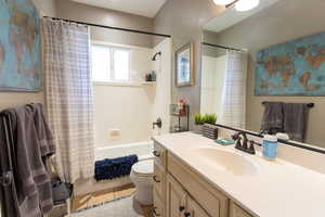 Full bathroom with toilet, tile patterned floors, shower / bathtub combination with curtain, and vanity