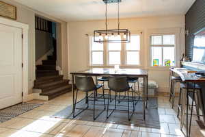Dining room featuring stairs, light tile patterned floors, and a chandelier