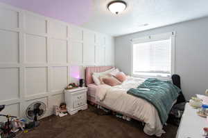 Bedroom featuring carpet floors, a textured ceiling, and visible vents