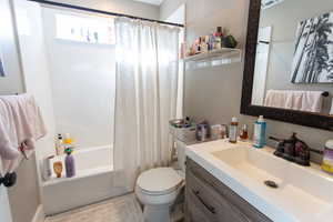 Bathroom with vanity, shower / bathtub combination with curtain, and toilet