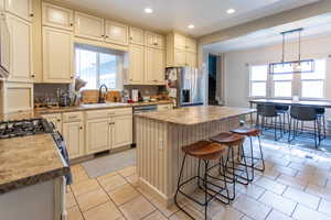 Kitchen with cream cabinets, a sink, light tile patterned floors, a wealth of natural light, and stainless steel appliances