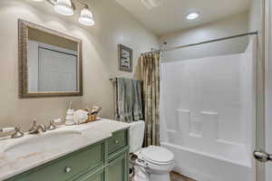 Bathroom with toilet, visible vents, shower / bath combination with curtain, and vanity