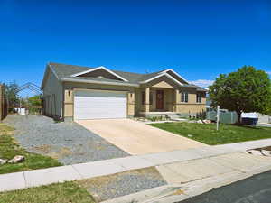 Ranch-style home featuring driveway, a garage, fence, and a front yard