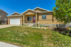 Ranch-style house featuring an attached garage, a front lawn, driveway, and stucco siding
