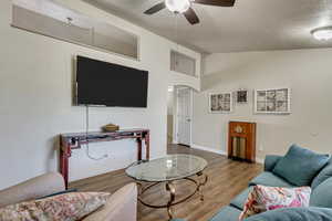 Living room with arched walkways, ceiling fan, vaulted ceiling, and wood finished floors