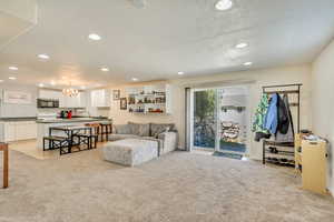 Living area featuring baseboards, light carpet, recessed lighting, and a notable chandelier