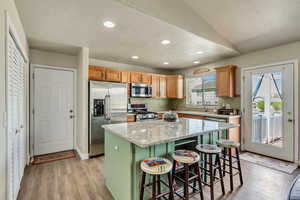 Kitchen featuring light wood-style floors, a kitchen breakfast bar, stainless steel appliances, recessed lighting, and a kitchen island