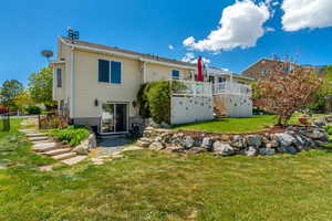 Rear view of house featuring stairway, a lawn, fence, and a wooden deck