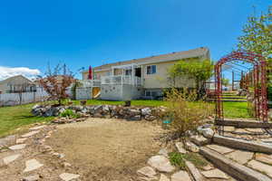 Back of house with a yard, fence, and a wooden deck