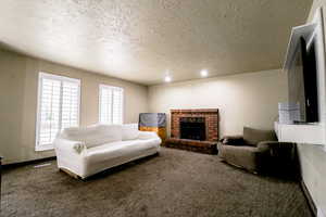 Living room with a fireplace, carpet, a textured ceiling, and a wealth of natural light